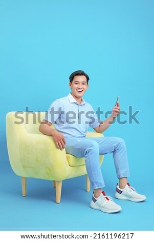 Asian handsome and cheerful young man using smart phone, sit on sofa, isolated on background Royalty-Free Stock Photo #2161196217