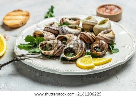 Escargots de Bourgogne Snails with herbs, butter, garlic, glass of white wine on a light background, gourmet food. Restaurant menu, Traditional French cuisine, Royalty-Free Stock Photo #2161206225
