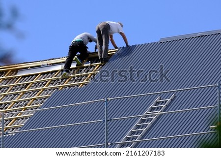 Two carpenters are replacing roof tiles in Norway. Royalty-Free Stock Photo #2161207183