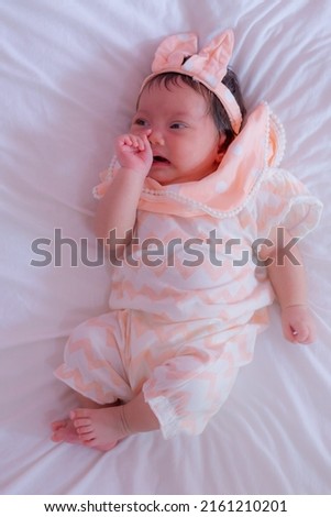 Baby girl crying in bed. Newborn with upset unhappy mean face