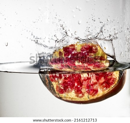 high speed photography of a delicious pomegranate entering a clear pool of water