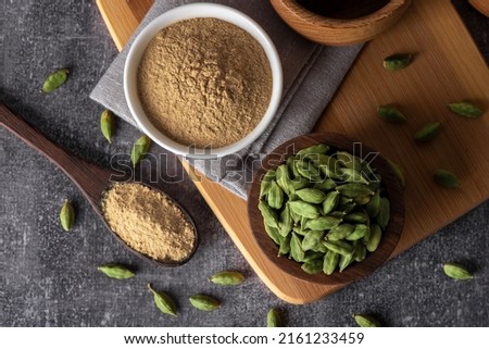 Green cardamom in wooden bowl and spoon. Dry cardamom spice. Cardamom seeds macro shot. Royalty-Free Stock Photo #2161233459