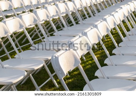 Rows of white folding chairs outside Royalty-Free Stock Photo #2161301809