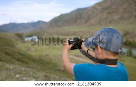 Traveling boy takes pictures of nature with a digital camera