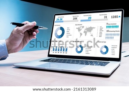 Businessman hand holding pen to display laptop with mockup chart presentation slide show background