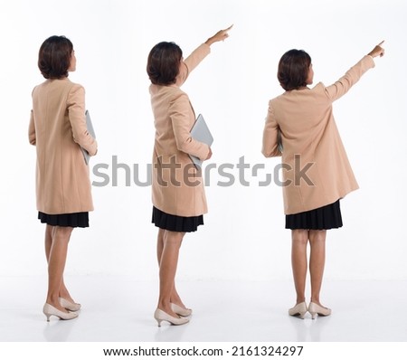 Full length 20s young Asian Business Woman businesswoman wear blazer skirt, pointing finger hand up. Office female carry laptop notebook coffee cup happy smile over white background isolated Royalty-Free Stock Photo #2161324297