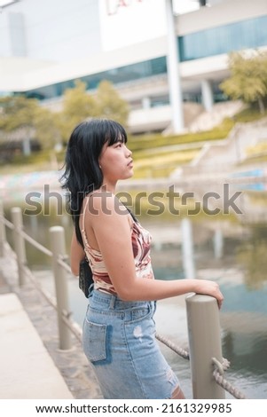 A fashionable woman with a a spaghetti strap top and denim skirt. A female with broad shoulders, a small bust and rectangular body shape. Royalty-Free Stock Photo #2161329985