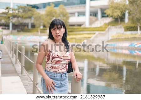 A fashionable woman with a a spaghetti strap top and denim skirt. A female with broad shoulders, a small bust and rectangular body shape. Royalty-Free Stock Photo #2161329987