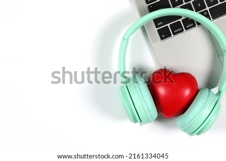 Green headphones with red heart placed on a laptop isolated on white background. Flat Lay photography with copy space.
