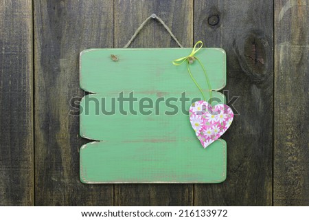 Blank green sign with floral heart hanging on rustic wooden door