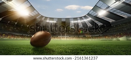 Opening season of games. Leather american football ball on grass of football field at stadium with spotlight. Concept of sport, art, energy, power. Poster for ad, design