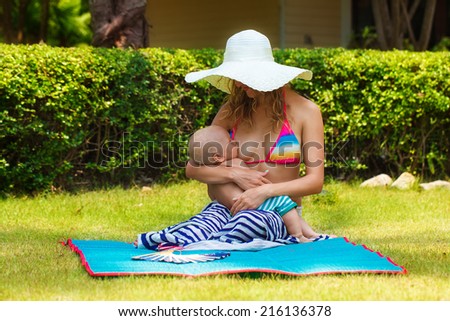 Beautiful mother breastfeeding child in the open air. Nature. Outdoor portrait of a happy family. The joy. The baby and mother in the tropics.