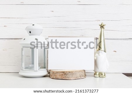 White card mockup. White invitation card on a light background with a Christmas lantern and a magic man. Festive mockup.