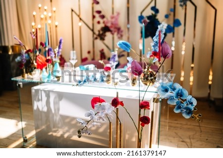 Wedding decorations. Festive table decorated with compositions of colored flowers. On the tables are plates, glasses, candles and cutlery