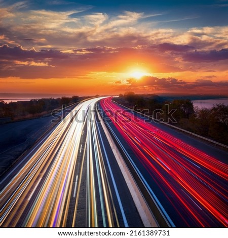 Light trails  lines of cars on the asphalt road. Sunset time with clouds and sun. Drive forward! Transport creative background. Long exposure, motion and blur.
 Royalty-Free Stock Photo #2161389731