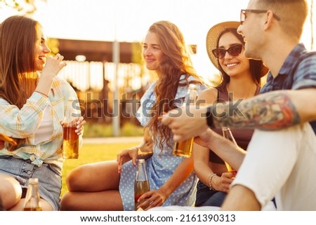 group of friends are enjoying pizza in the park. Men and women sit on the grass around a pizza box. The concept of a picnic in the park, friends together in nature