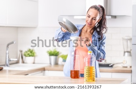 Woman pouring used cooking oil for recycling and reuse into the plastic bottle to be made in the factory into the fuel additive.  Royalty-Free Stock Photo #2161393267