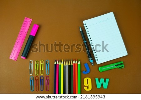 Back to school concept with school supplies, crayons, pencils, paper clips,alphabet on brown background