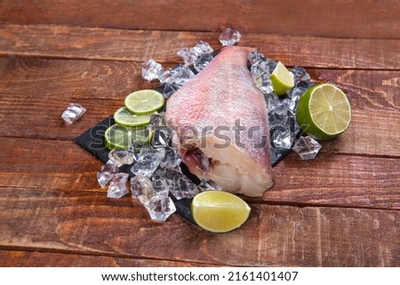 Raw fish on a stone board. Perch fresh in ice and with lime. perch on a board in the ice