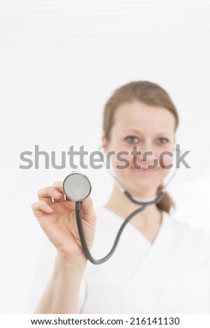 Nurse smiling holding stethoscope against white background
