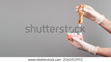 Banner with dentist hands pulling tooth with forceps out of jaw model. Teeth extraction, stomatology concept. Dental diseases treatment. Copy space. High quality photo Royalty-Free Stock Photo #2161415911