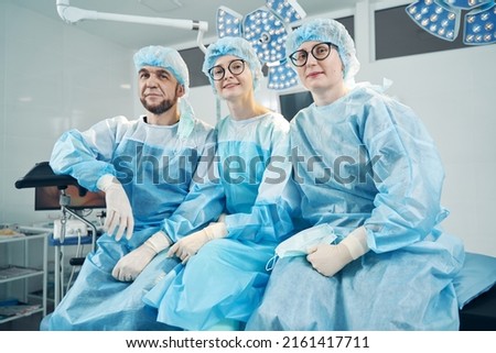 Medic sitting with female co-workers on operation bed