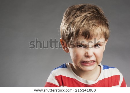 Young boy looking angry, clenching teeth against gray background Royalty-Free Stock Photo #216141808