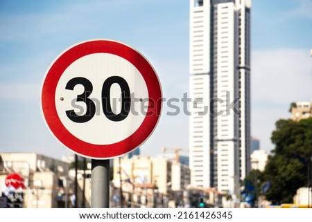 Speed limit traffic signs in israeli town Ramat-Gan with a high building on the background