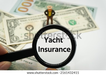 Yacht Insurance.Magnifying glass showing the words.Background of banknotes and coins.basic concepts of finance.Business theme.Financial terms.