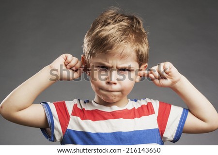 Young boy covering ears against gray background Royalty-Free Stock Photo #216143650