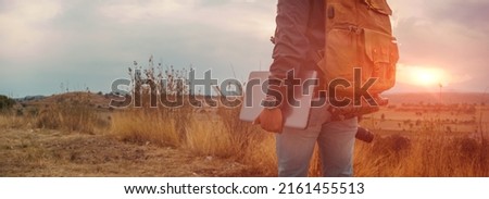  unrecognizable man with a laptop walking at sunset