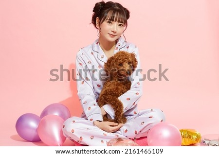 Young woman in pajamas with a toy poodle Royalty-Free Stock Photo #2161465109