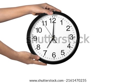 Hand holds a large black clock on a white background. 