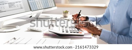 Businessperson Calculating Invoice Using Calculator At Desk Royalty-Free Stock Photo #2161473329