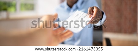 Close-up Of A Businessman's Hand Giving Cheque To Colleague Royalty-Free Stock Photo #2161473355