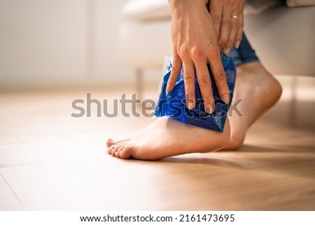Close-up Of A Woman's Hand Applying Ice Gel Pack On Her Ankle