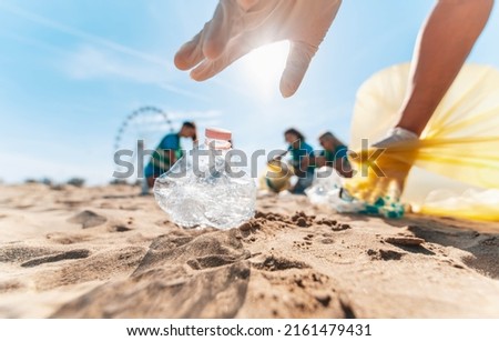 Group of eco volunteers picking up plastic trash on the beach - Activist people collecting garbage protecting the planet - Ocean pollution, environmental conservation and ecology concept Royalty-Free Stock Photo #2161479431