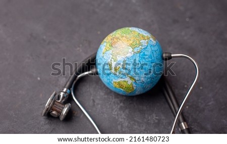 Green Earth day, Save the wold and Global healthcare concept. Stethoscope wrapped around globe on dark background.
