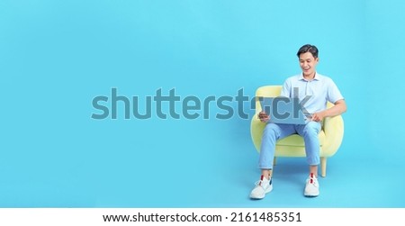 Work from home concept with an Asian young handsome guy, with laptop computer, isolated on blue background