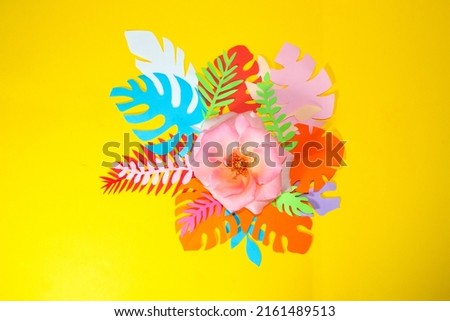 pink rose on colorful jungle leaves on yellow background, creative tropical design, summer romantic scene
