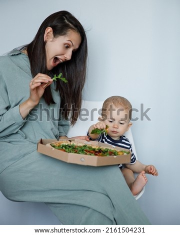 mom and son eating pizza. Mom feeds her son pizza. vegetarian pizza. delicious eating pizza.