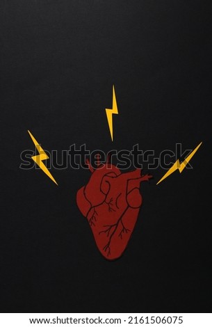 Heart diseases. Paper heart with sparks on black background. Creative layout
