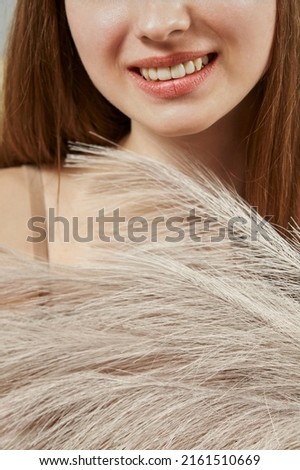 a wide smile and a large soft feather on the face. smoothness and softness of the skin