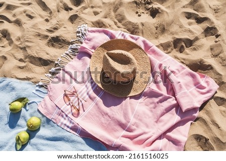 Summer beach accessories flat lay on sand background. Holiday travel, tropical concept. Straw hat, sunglasses, towel and fruits. Sun shadow and sunlight. Royalty-Free Stock Photo #2161516025