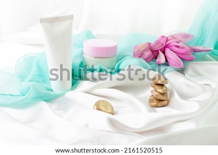 tube and jar without label, product mockup for skin care products, with white satin golden zen stones and magnolia flowers