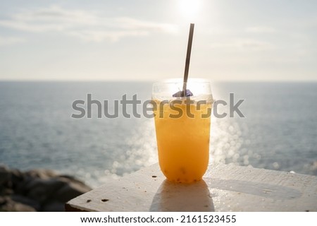 Close-up cups Orange juice on table seaside during sunset sky United States. Fresh orange cocktail in glass summer holiday background. Water drink summer Copy space.