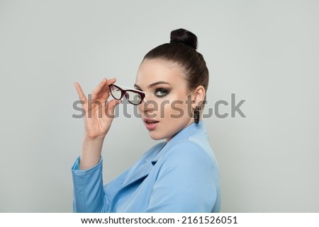 Attractive young woman holding glasses and looking at camera on white background