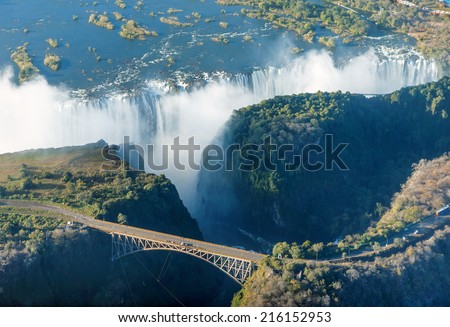 The Victoria falls is the largest curtain of water in the world (1708 m wide). The falls and the surrounding area is the National Parks and World Heritage Site (helicopter view) - Zambia, Zimbabwe Royalty-Free Stock Photo #216152953