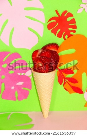 ice cream with strawberries on a green-pink background surrounded by jungle tropical leaves, creative summer design