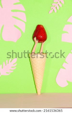 ice cream with strawberry held by hands from the cone, creative art design on a green pink background with pink jungle leaves
